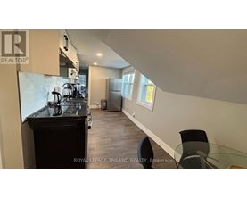A kitchen with a black countertop and a dining table with chairs.
