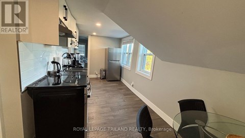 A kitchen with a black countertop and a dining table with chairs.
