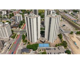 A view of a city with tall buildings, a pool, and a parking lot.