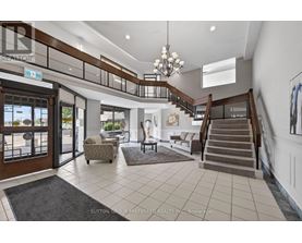A spacious foyer with a staircase, chairs, and a rug.