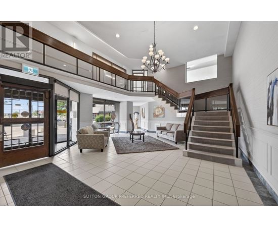 A spacious foyer with a staircase, chairs, and a rug.