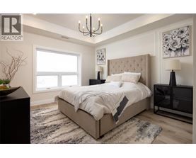A bedroom with a large bed, a chandelier, and a vase on a side table.