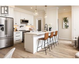 A kitchen with white cabinets and a white island with three chairs.