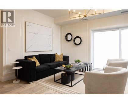 A living room with a black couch and a white wall.