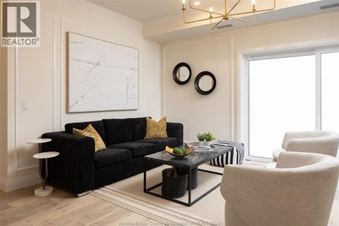 A living room with a black couch and a white wall.