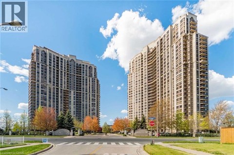Two tall buildings are situated next to each other with a street in between.
