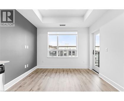 A spacious room with a large window and wooden flooring.
