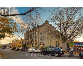 A street view with cars parked on the side and a building in the background.
