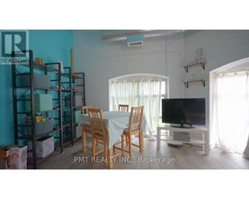 A living room with a dining table, chairs, and a television.