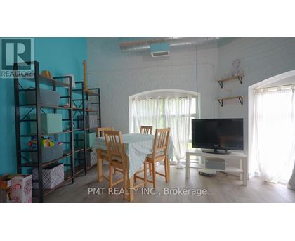A living room with a dining table, chairs, and a television.