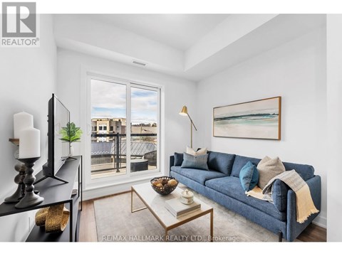 A living room with a blue couch and a painting on the wall.