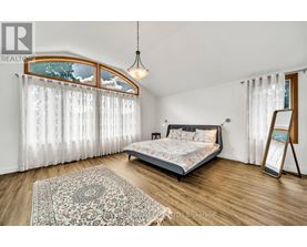 A bedroom with a bed, a rug, and a window with curtains.