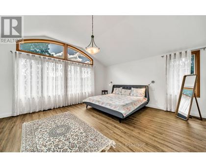 A bedroom with a bed, a rug, and a window with curtains.