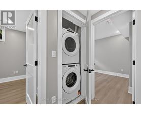 A white washing machine is in a white cabinet in a white room.