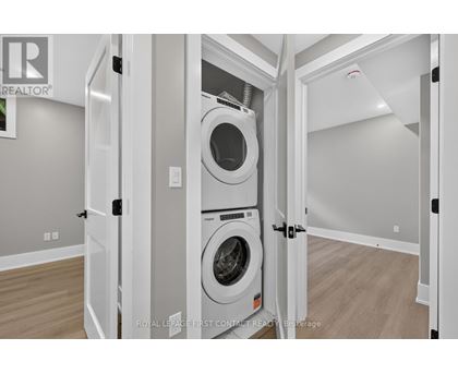 A white washing machine is in a white cabinet in a white room.