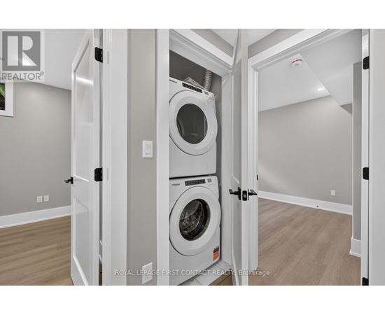 A white washing machine is in a white cabinet in a white room.