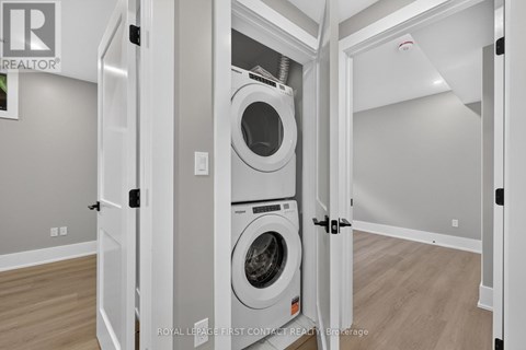 A white washing machine is in a white cabinet in a white room.