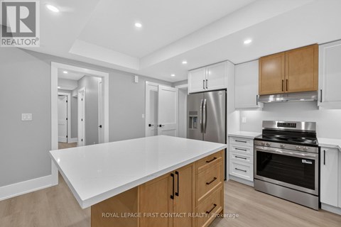 A modern kitchen with a white countertop and stainless steel appliances.