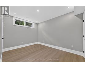 A room with wooden flooring and a window showing trees outside.