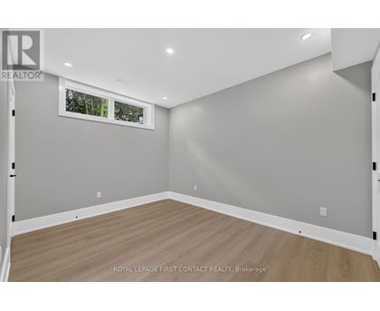 A room with wooden flooring and a window showing trees outside.