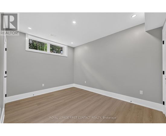 A room with wooden flooring and a window showing trees outside.