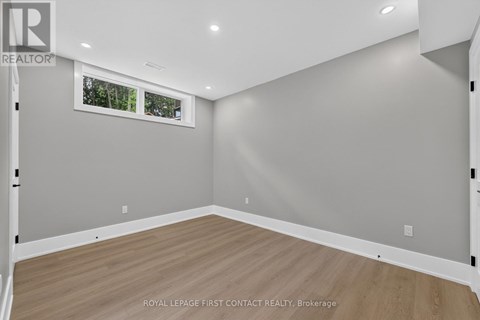 A room with wooden flooring and a window showing trees outside.