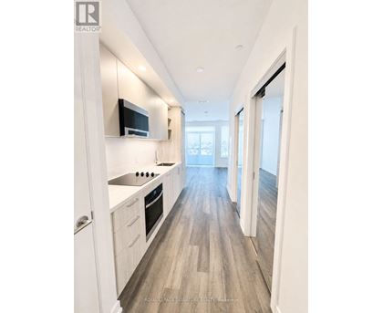 A modern kitchen with white cabinets and a wooden floor.