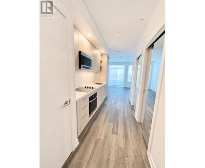 A modern kitchen with white cabinets and a flat screen TV mounted above the stove.