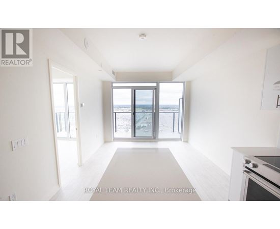 A spacious, empty room with a large window overlooking a beach.