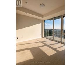A room with wooden flooring and a large window overlooking a balcony.