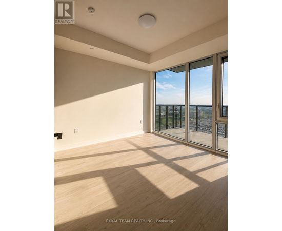 A room with wooden flooring and a large window overlooking a balcony.