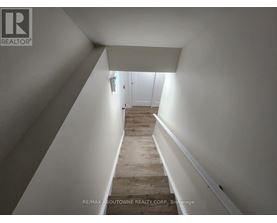 A hallway with wooden floors and white walls leading to a door.