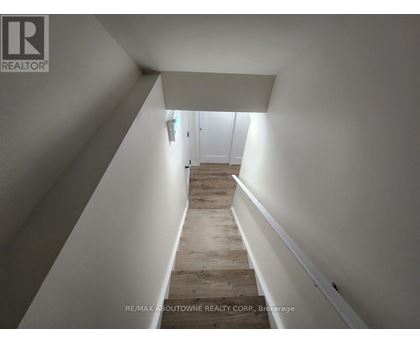 A hallway with wooden floors and white walls leading to a door.