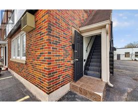 A red brick building with a black door and steps leading up to it.