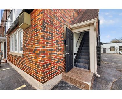 A red brick building with a black door and steps leading up to it.