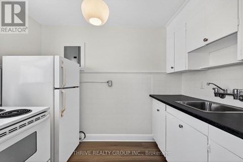A small kitchen with white cabinets and a black countertop.