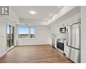 A modern kitchen with white appliances and wooden floors.