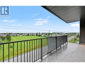 A balcony with a metal railing overlooks a residential area.