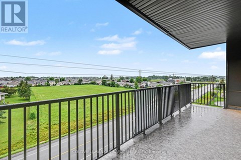 A balcony with a metal railing overlooks a residential area.