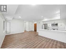 A spacious kitchen and living room with wood flooring and white walls.
