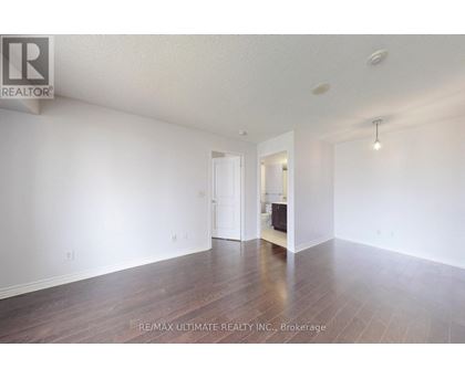 A spacious room with wooden floors and white walls, ready for staging.