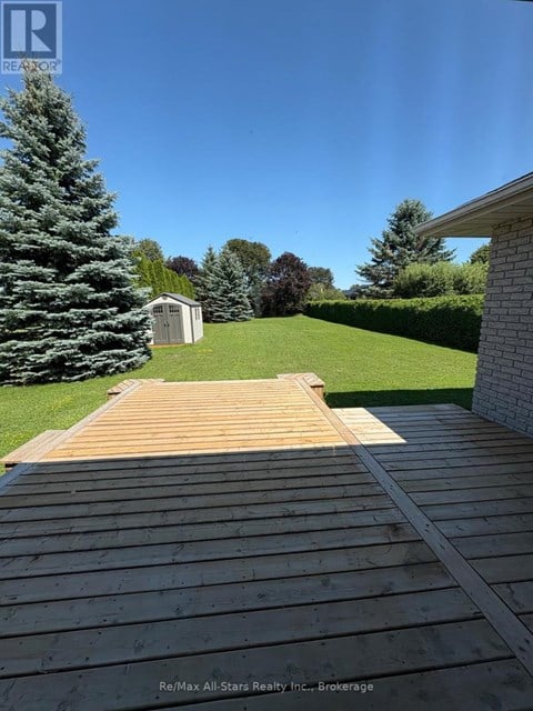 A wooden deck leads to a small building in a grassy yard.