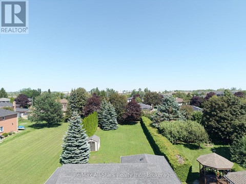 A bird's eye view of a residential area with houses, trees, and a gazebo.