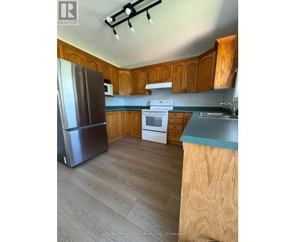 A kitchen with wooden cabinets and a stainless steel refrigerator.