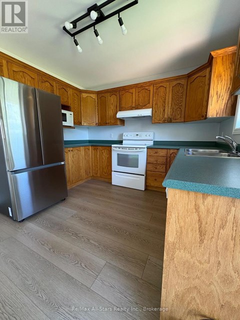 A kitchen with wooden cabinets and a stainless steel refrigerator.