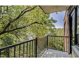 A balcony with a black railing and a view of trees and a building.