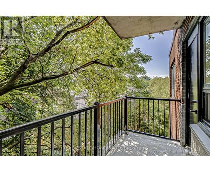 A balcony with a black railing and a view of trees and a building.