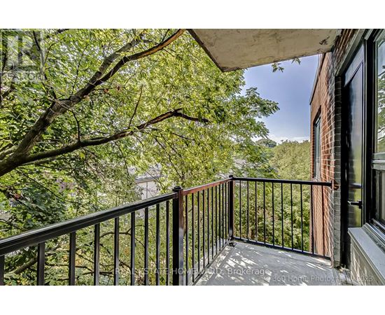 A balcony with a black railing and a view of trees and a building.