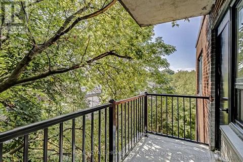A balcony with a black railing and a view of trees and a building.