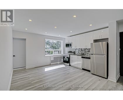 A modern kitchen with white cabinets and a stainless steel refrigerator.
